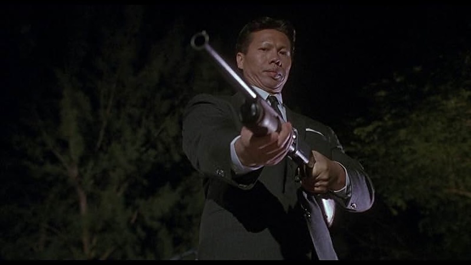 Bolo Yeung, un fusil à la main, dans Double Impact