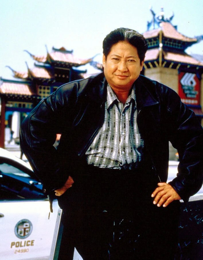 Sammo Hung, devant une voiture de police — Le Flic de Shanghaï