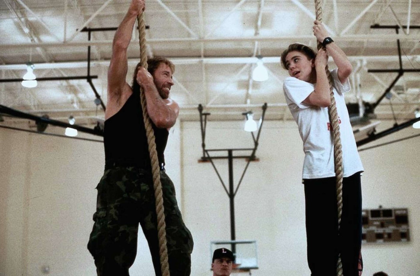 Deux personnages grimpent à la corde dans un gymnase, dans une scène du film Sidekicks