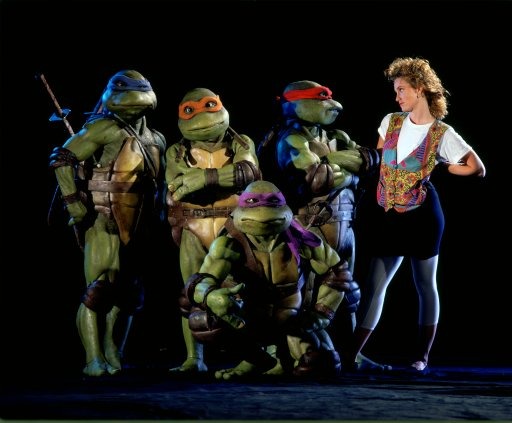 Les quatre Tortues Ninjas en costume, aux côtés d'une jeune femme